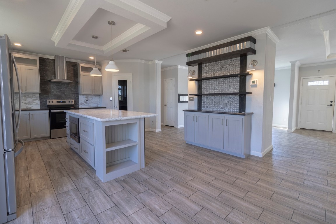 425 High View Ranch Drive Cedar Creek, TX 78612 - Photo 29 of 36 Kitchen with open shelves, crown molding, decorative backsplash, appliances with stainless steel finishes, and pendant lighting