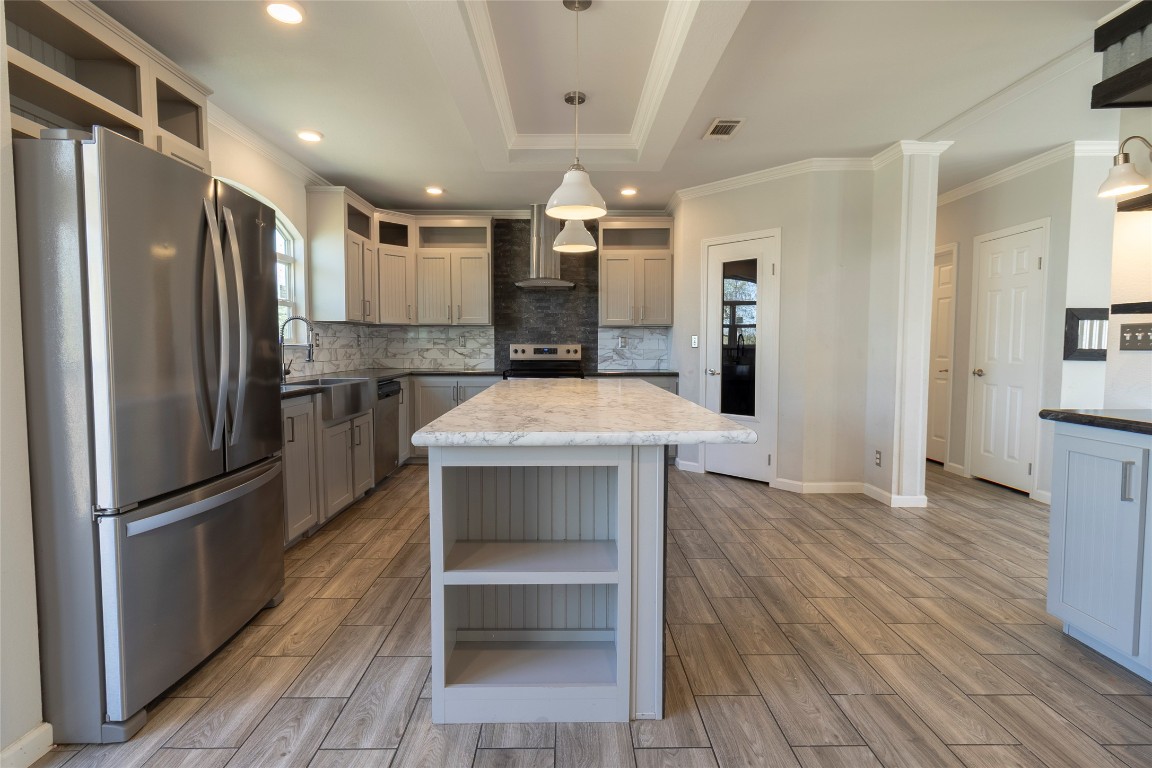 425 High View Ranch Drive Cedar Creek, TX 78612 - Photo 32 of 36 Kitchen featuring open shelves, stainless steel appliances, ornamental molding, pendant lighting, and wood tiled floors