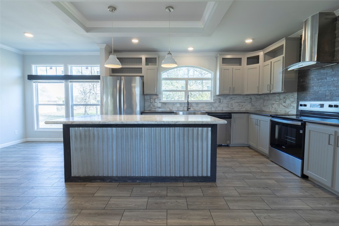 425 High View Ranch Drive Cedar Creek, TX 78612 - Photo 33 of 36 Kitchen featuring appliances with stainless steel finishes, wall chimney exhaust hood, decorative backsplash, crown molding, and pendant lighting