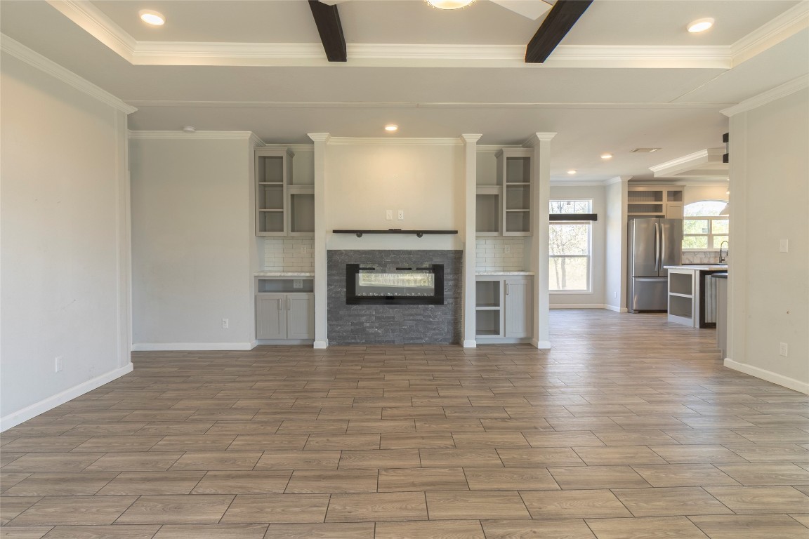 425 High View Ranch Drive Cedar Creek, TX 78612 - Photo 36 of 36 Unfurnished living room with a glass covered fireplace, recessed lighting, wood tiled floors, ceiling fan, and crown molding