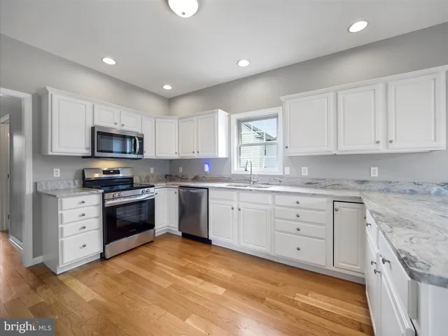 a kitchen with granite countertop white cabinets and stainless steel appliances