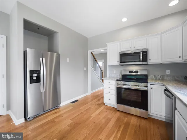 a kitchen with stainless steel appliances a stove a microwave and a hard wood floor