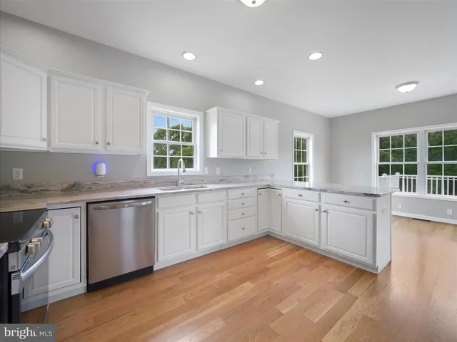 a kitchen with granite countertop white cabinets a sink a window and stainless steel appliances
