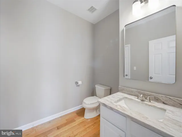 a bathroom with a granite countertop sink a toilet and a mirror