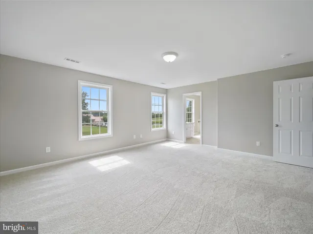 a view of an empty room with wooden floor and windows