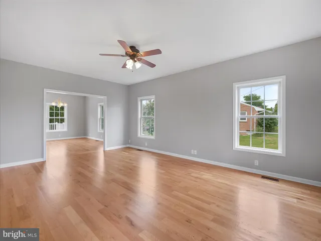a view of an empty room with a window and wooden floor