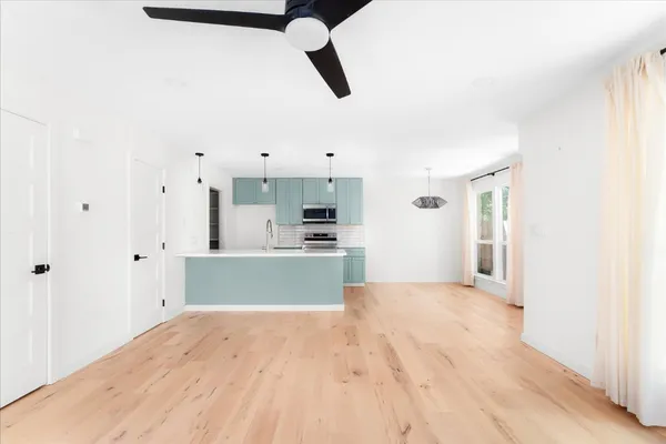 a view of kitchen and empty room with wooden floor