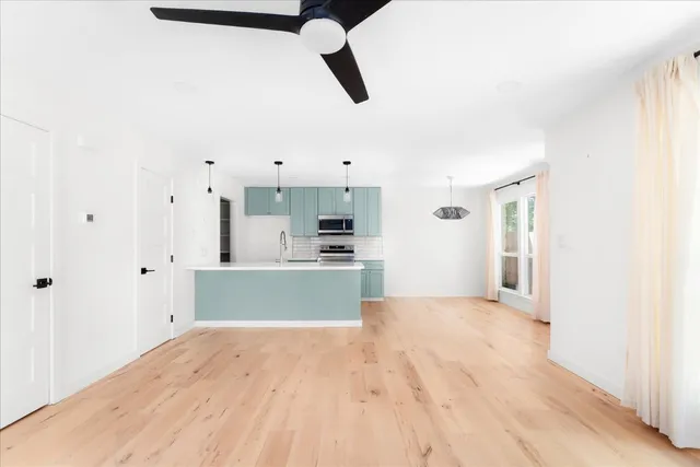 a view of kitchen and empty room with wooden floor