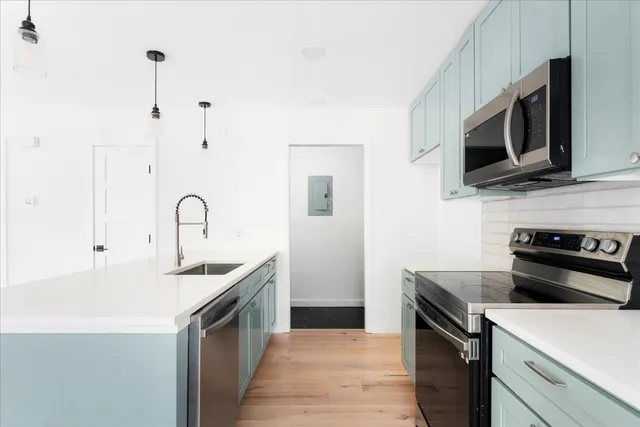 a kitchen with stainless steel appliances a stove microwave and sink