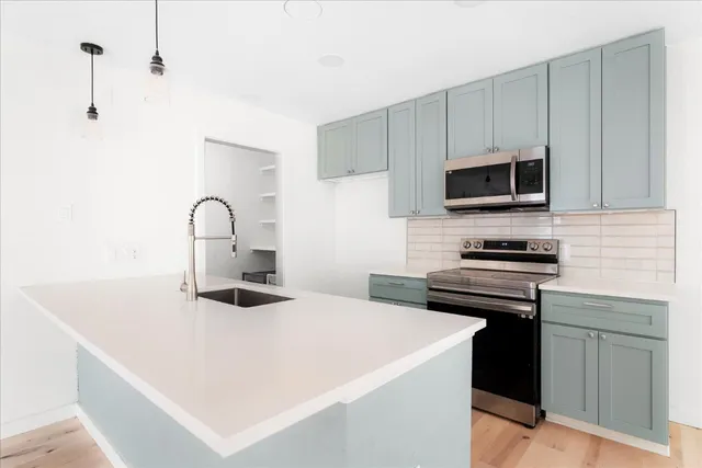 a kitchen with stainless steel appliances a stove microwave and sink