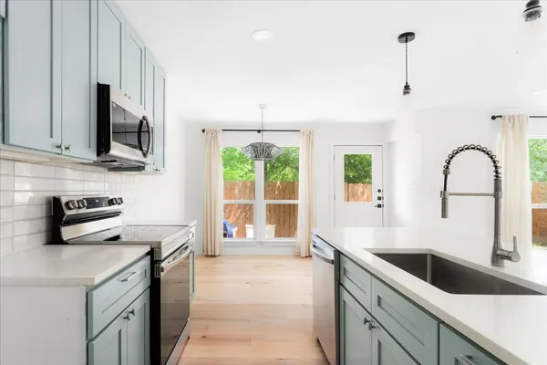 a kitchen with a sink a counter top space cabinets and stainless steel appliances