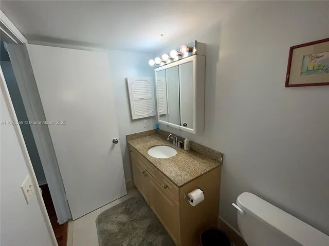 a bathroom with a granite countertop sink toilet and mirror