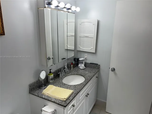 a bathroom with a granite countertop sink a mirror and shower curtain