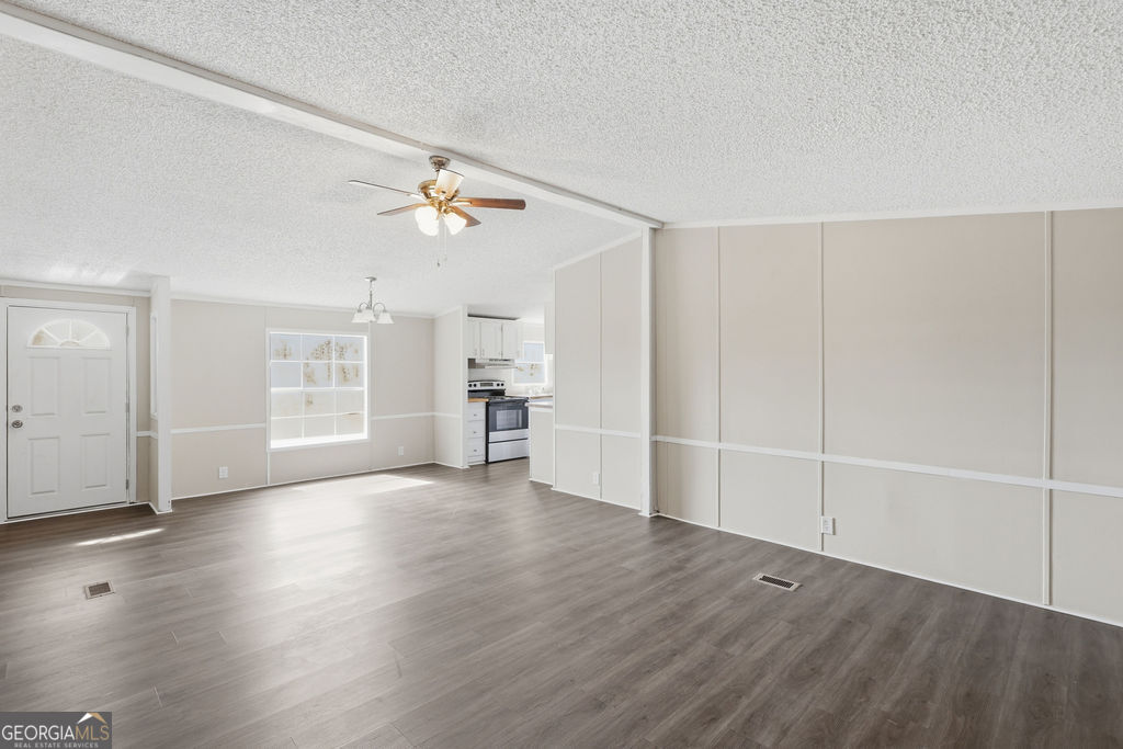 196 Barn Rd Circle Jesup, GA 31545 - Photo 6 of 31 an empty room with wooden floor chandelier fan and windows