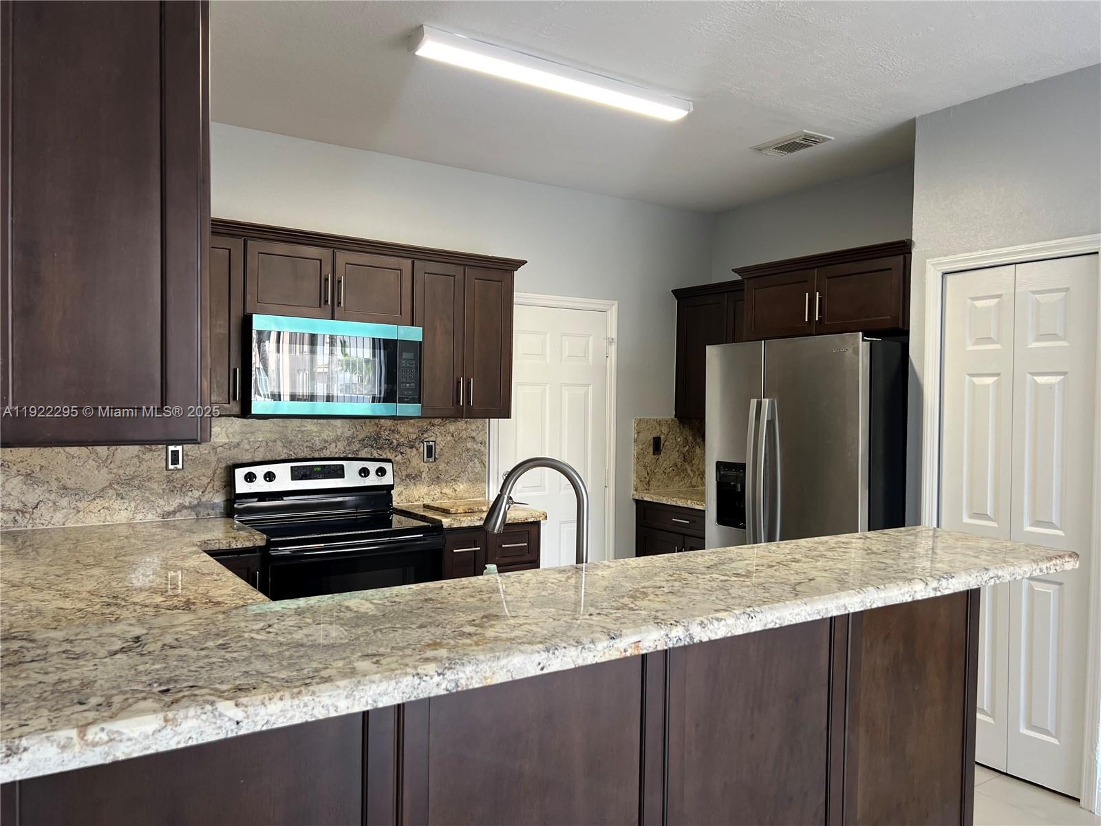 27510 Southwest 138th Path Homestead, FL 33032 - Photo 10 of 35 a kitchen with granite countertop a refrigerator stove and sink