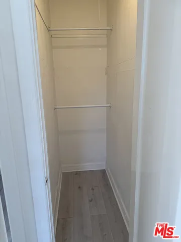 a view of an empty room with wooden floor and closet