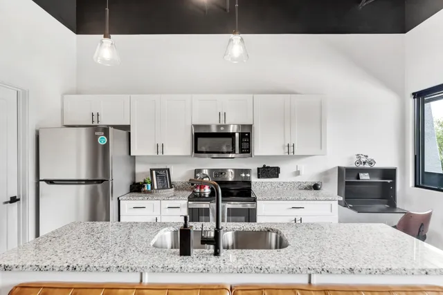 a kitchen with stainless steel appliances granite countertop a refrigerator sink and stove