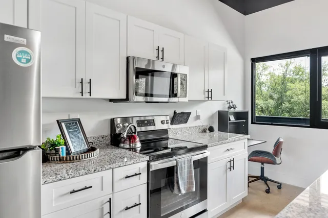 a kitchen with stainless steel appliances granite countertop a stove a sink and a microwave