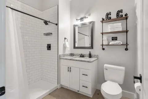 a bathroom with a granite countertop toilet sink and mirror