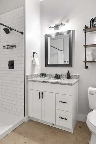 a bathroom with a granite countertop sink a toilet and a mirror