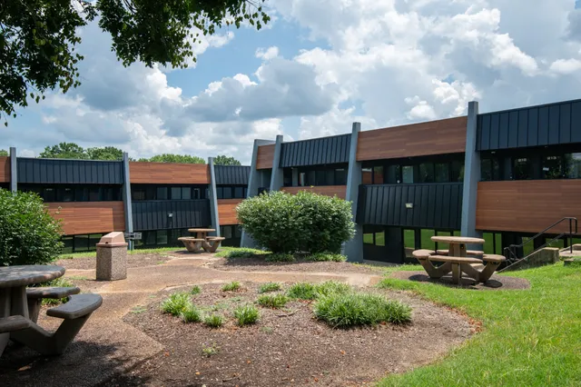 a view of a house with a yard and table and chairs under an umbrella