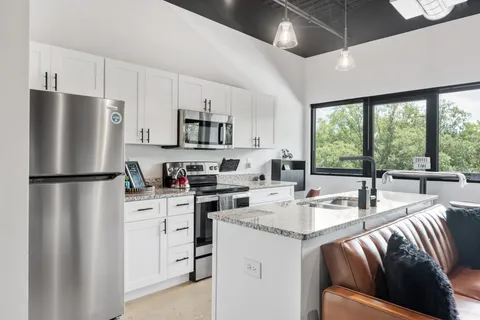 a kitchen with stainless steel appliances granite countertop a refrigerator a stove a sink a dining table and chairs with the ocean view