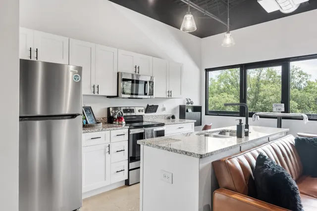 a kitchen with stainless steel appliances granite countertop a refrigerator a stove a sink a dining table and chairs with the ocean view