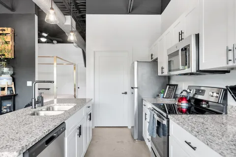a kitchen with stainless steel appliances granite countertop a sink stove and cabinets