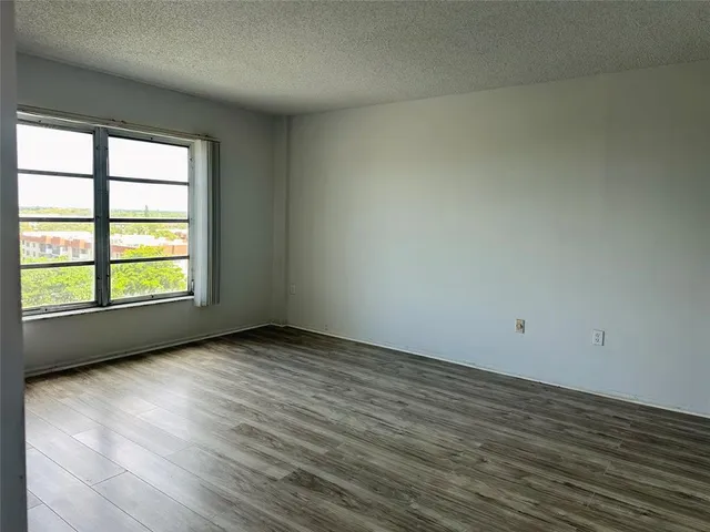 a view of an empty room with wooden floor and closet
