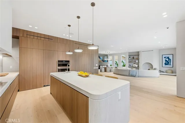 a view of a kitchen with kitchen island a sink a counter top space and living room view