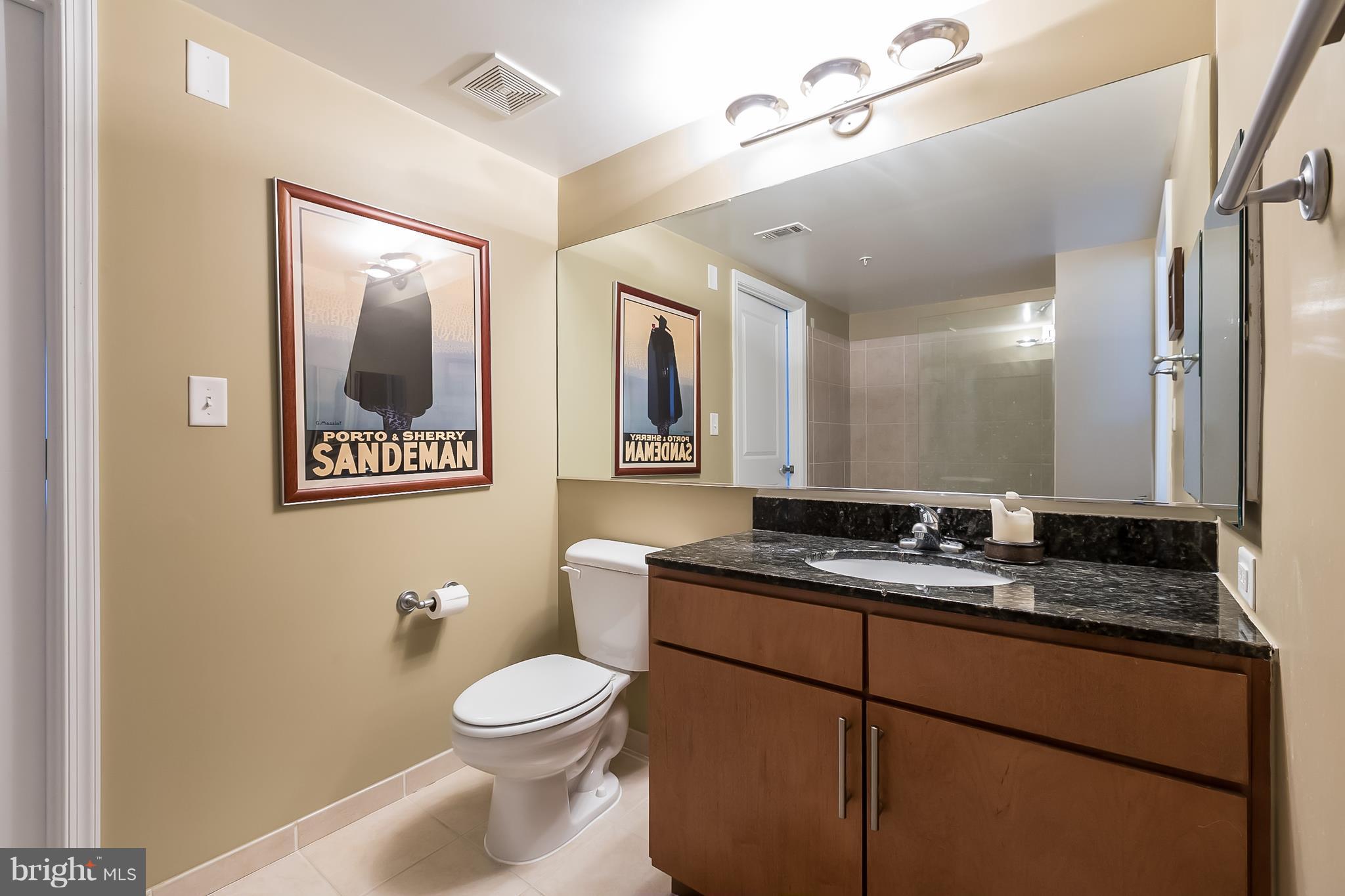 915 E Street Northwest, Unit 613 Washington, DC 20004 - Photo 12 of 30 a bathroom with a granite countertop toilet sink and mirror