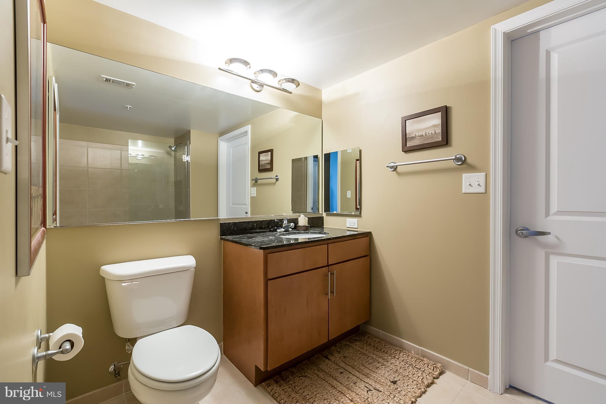 915 E Street Northwest, Unit 613 Washington, DC 20004 - Photo 10 of 30 a bathroom with a granite countertop toilet sink and mirror