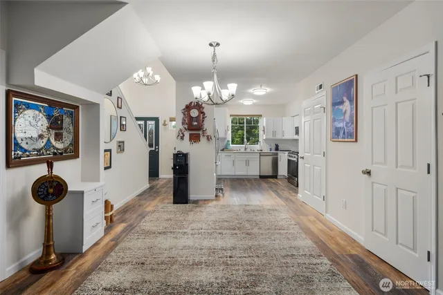 a view of a hallway to room with wooden floor and windows