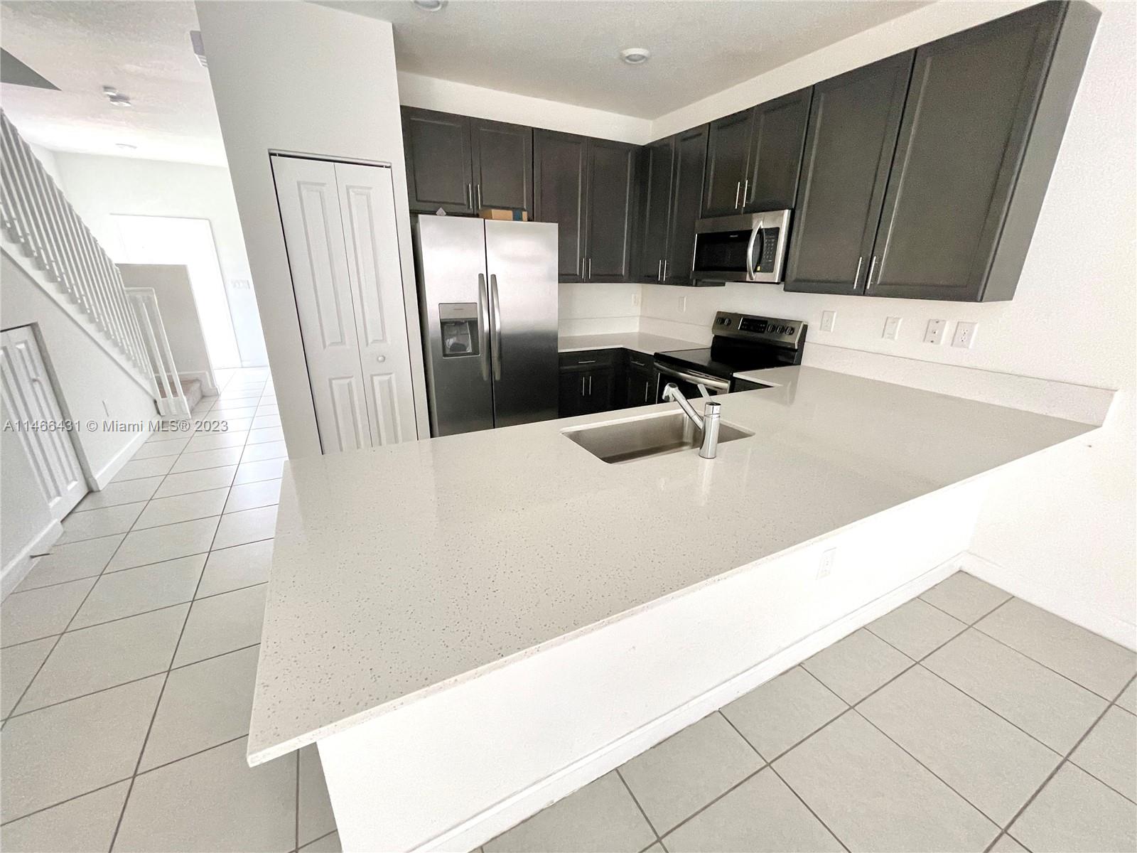 23373 Southwest 129th Path, Unit 23373 Miami, FL 33186 - Photo 10 of 20 a kitchen with stainless steel appliances a refrigerator a sink a stove a microwave and cabinets
