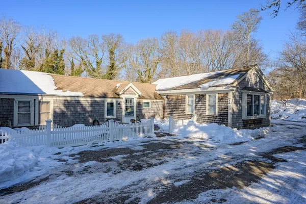 a front view of a house with a yard covered with snow
