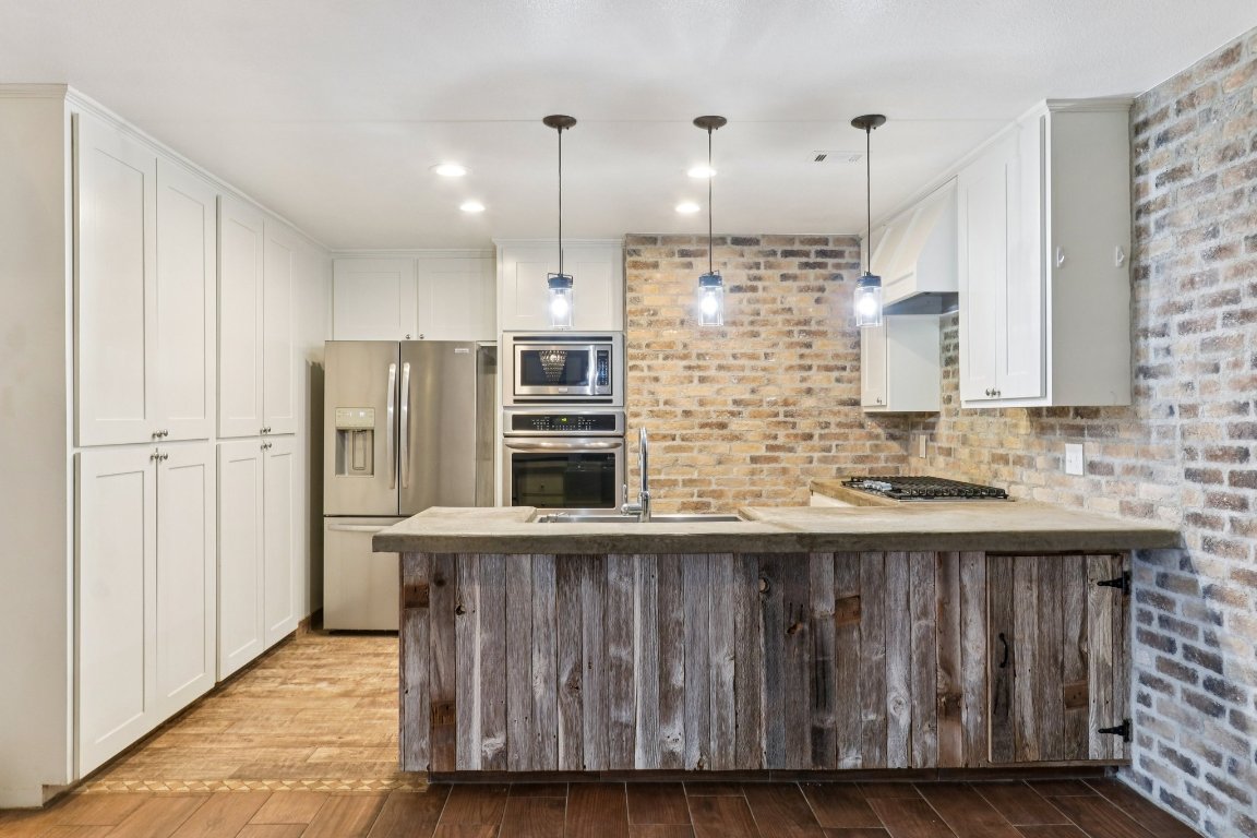 24369-2 Bingham Creek Road, Unit 12 Leander, TX 78641 - Photo 8 of 22 a kitchen with stainless steel appliances granite countertop a refrigerator a sink and wooden cabinets