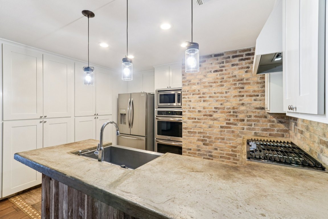 24369-2 Bingham Creek Road, Unit 12 Leander, TX 78641 - Photo 9 of 22 a kitchen with kitchen island a sink appliances and cabinets