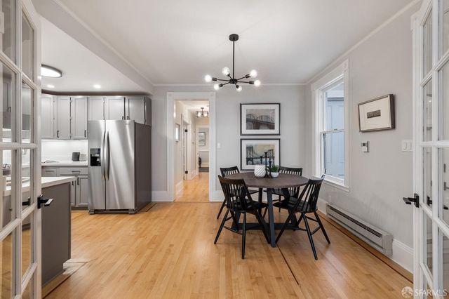 a kitchen with stainless steel appliances granite countertop a dining table chairs and refrigerator