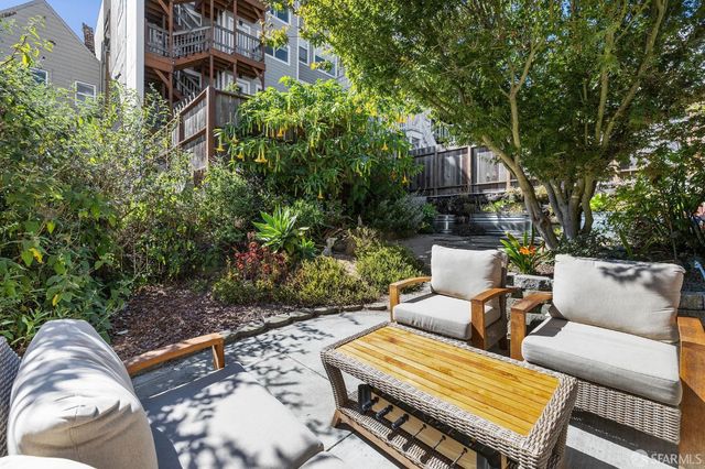 a view of a patio with table and chairs with wooden fence and plants
