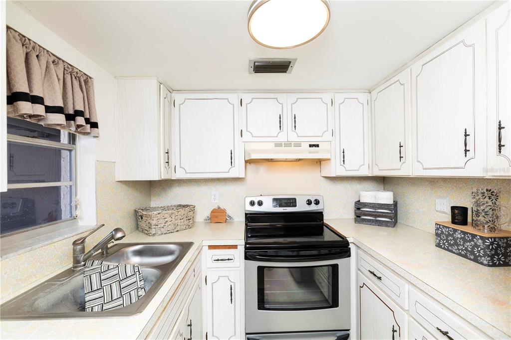 4609 Marine Parkway, Unit 203 New Port Richey, FL 34652 - Photo 11 of 25 a kitchen with granite countertop a sink a stove and cabinets