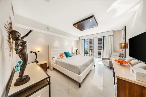 a bedroom with bed and a flat tv screen on the dresser