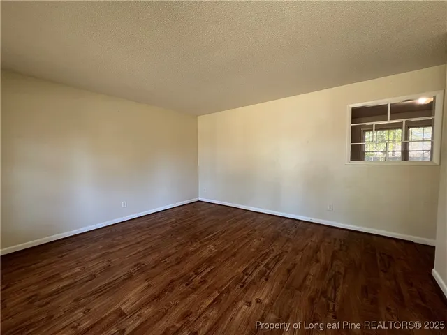 a view of an empty room with wooden floor and windows