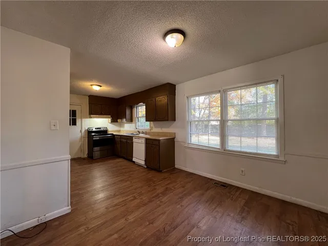 a kitchen with stainless steel appliances a sink wooden floor and a window