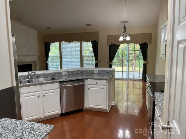 a kitchen with stainless steel appliances granite countertop a stove a sink and a wooden floors