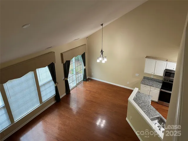 a view of an empty room with wooden floor and furniture