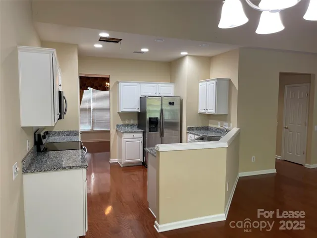 a kitchen with stainless steel appliances granite countertop a sink and a refrigerator