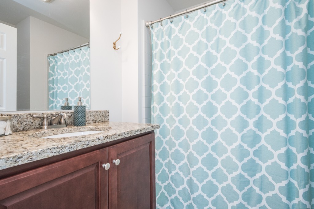 143 Broad Street, Unit 20 Hudson, MA 01749 - Photo 19 of 30 a bathroom with a granite countertop sink a mirror and shower curtain