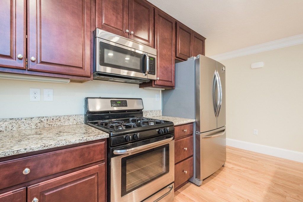 143 Broad Street, Unit 20 Hudson, MA 01749 - Photo 7 of 30 a kitchen with stainless steel appliances granite countertop a refrigerator stove and microwave