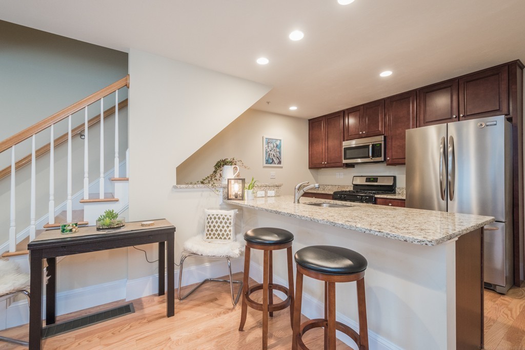 143 Broad Street, Unit 20 Hudson, MA 01749 - Photo 10 of 30 a kitchen with stainless steel appliances granite countertop a refrigerator a stove a sink dishwasher and white cabinets with wooden floor