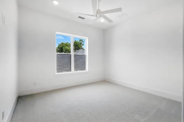 an empty room with a window and a ceiling fan